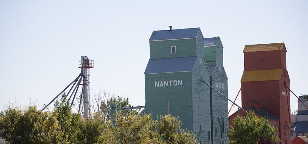 Exterior of two grain elevator structures. The buildings are tall blue and red wooden structures.